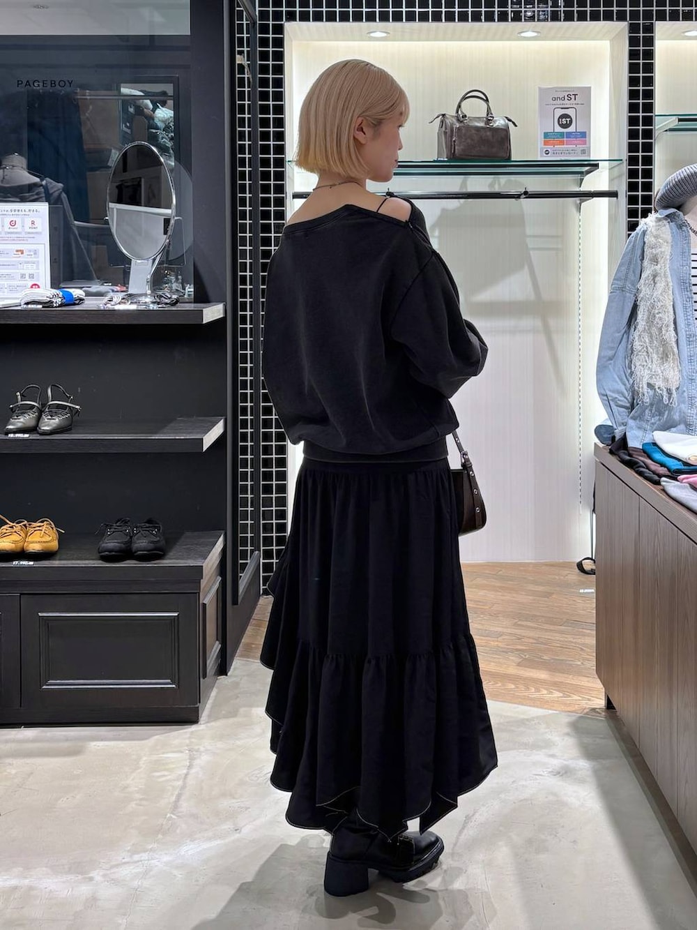 ブラック系のブーツ、ブラック系のスカート、ブラウン系のハンドバッグを着用したレディースの春コーディネートの4枚目の写真