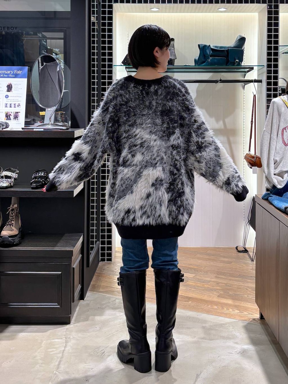 ホワイト系のタンクトップ、ブラック系のカーディガン/ボレロ、ブラック系のブーツを着用したレディースの秋コーディネートの3枚目の写真