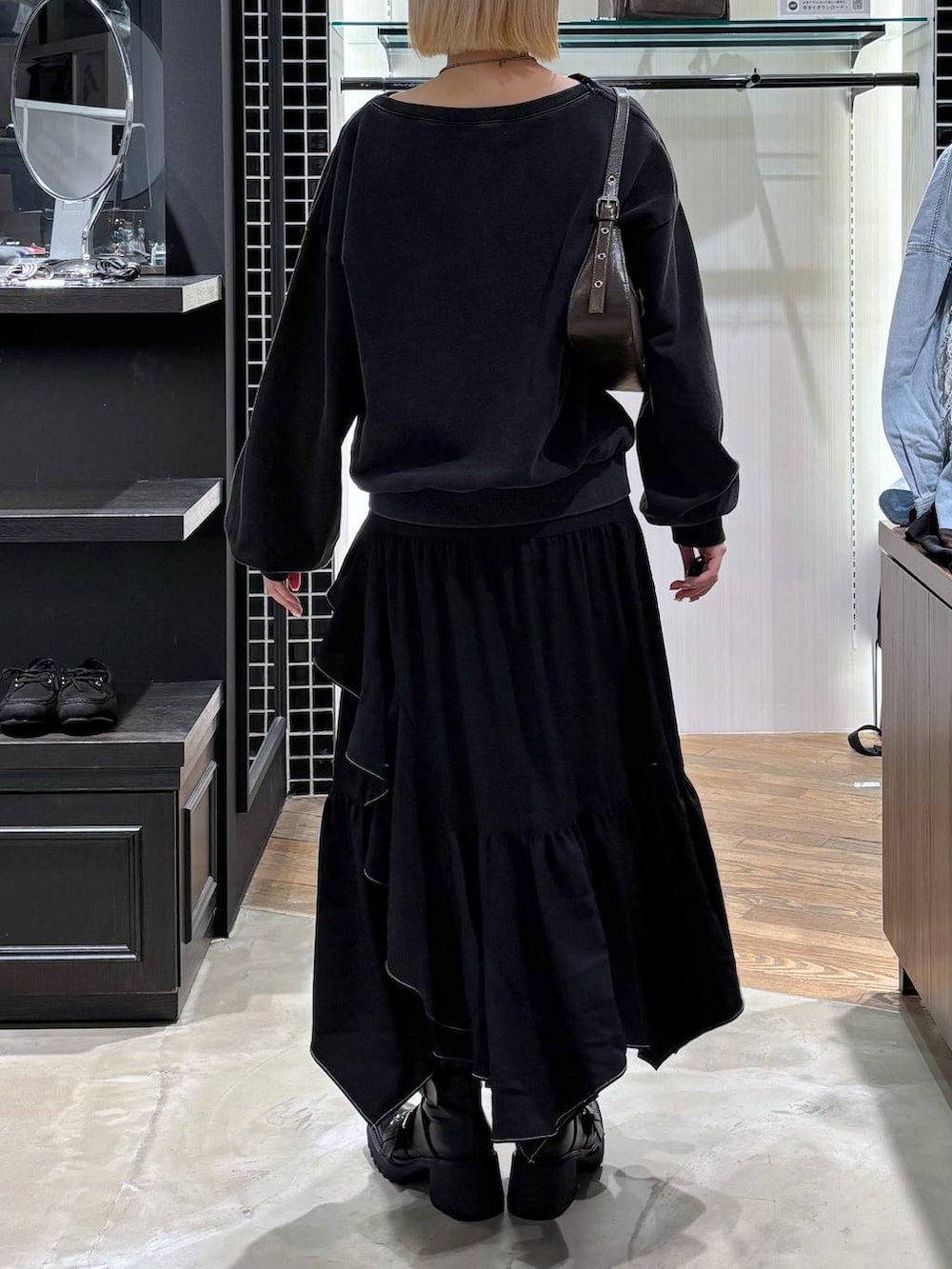 ブラック系のブーツ、ブラック系のスカート、ブラウン系のハンドバッグを着用したレディースの春コーディネートの3枚目の写真