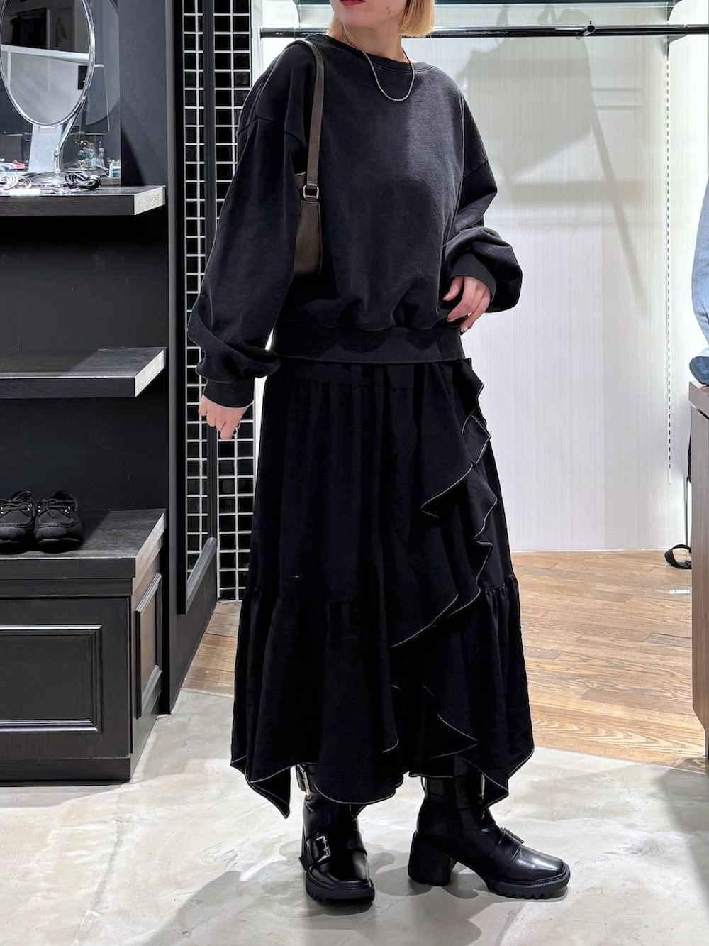 ブラック系のブーツ、ブラック系のスカート、ブラウン系のハンドバッグを着用したレディースの春コーディネートの8枚目の写真