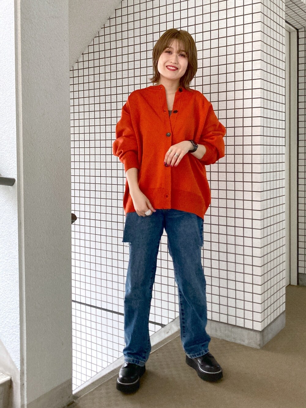 グレー系のタンクトップ、オレンジ系のカーディガン/ボレロ、ブルー系のデニムパンツを着用したレディースの秋コーディネートの2枚目の写真