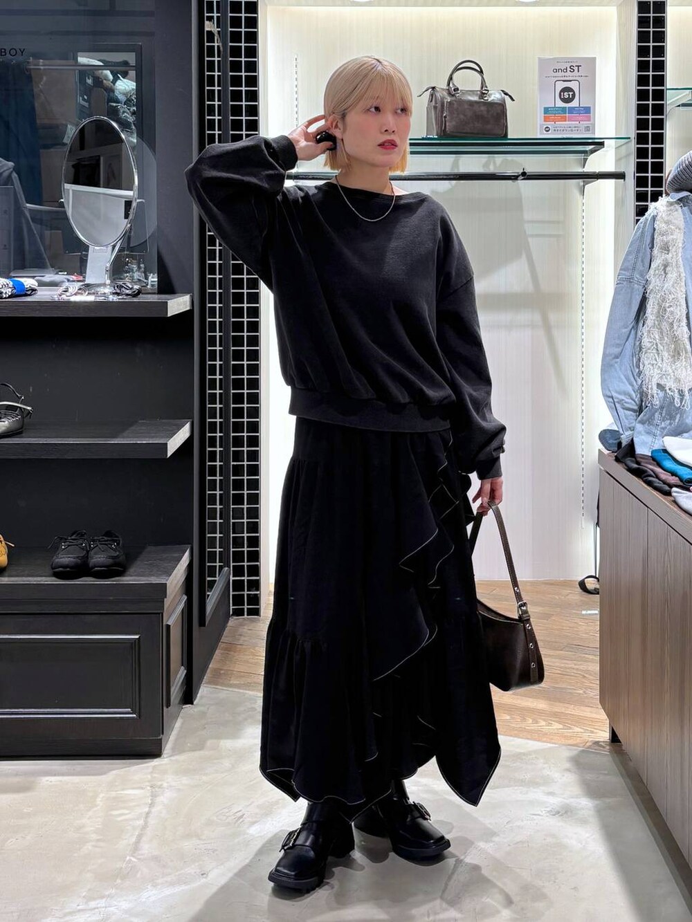 ブラック系のブーツ、ブラック系のスカート、ブラウン系のハンドバッグを着用したレディースの春コーディネートの9枚目の写真