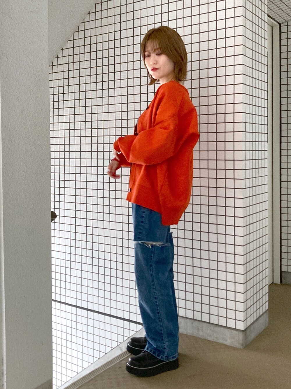 グレー系のタンクトップ、オレンジ系のカーディガン/ボレロ、ブルー系のデニムパンツを着用したレディースの秋コーディネートの3枚目の写真