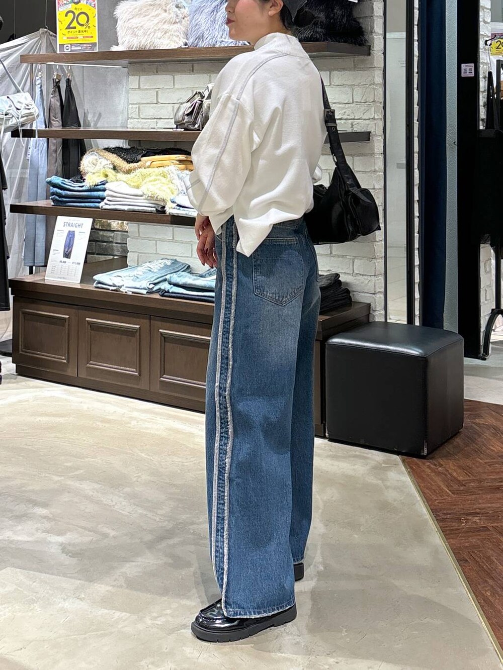 ホワイト系のニット/セーター、ブラック系のショルダーバッグ、ブルー系のデニムパンツを着用したレディースの冬コーディネートの4枚目の写真