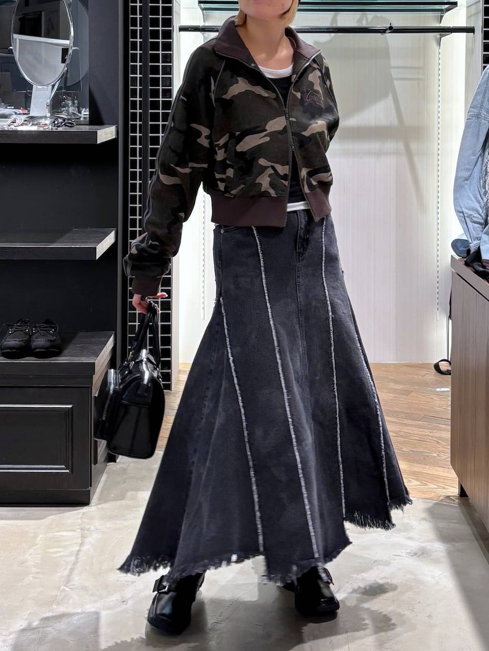 ブラック系のブーツ、ブラック系のショルダーバッグ、ブラック系のデニムスカートを着用したレディースの春コーディネートの5枚目の写真