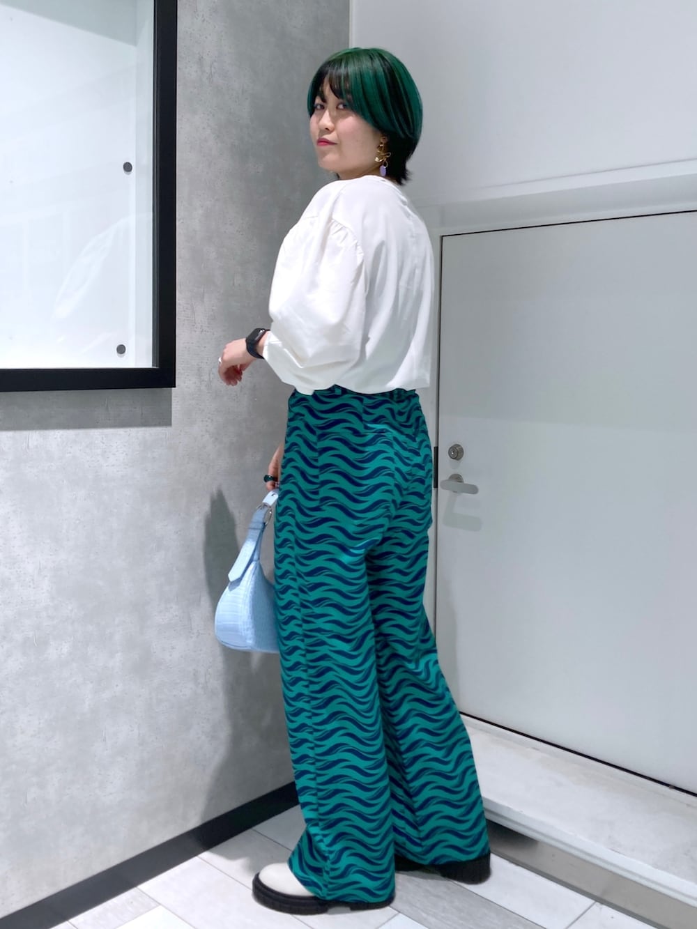 ホワイト系のTシャツ/カットソー、ブラック系のミリタリージャケット、グリーン系のパンツを着用したレディースの春コーディネートの5枚目の写真