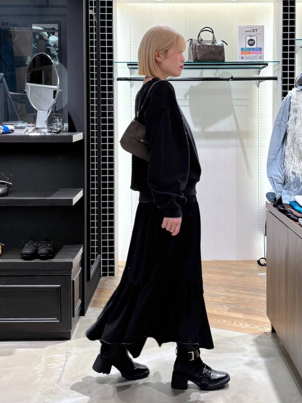 ブラック系のブーツ、ブラック系のスカート、ブラウン系のハンドバッグを着用したレディースの春コーディネートの7枚目の写真