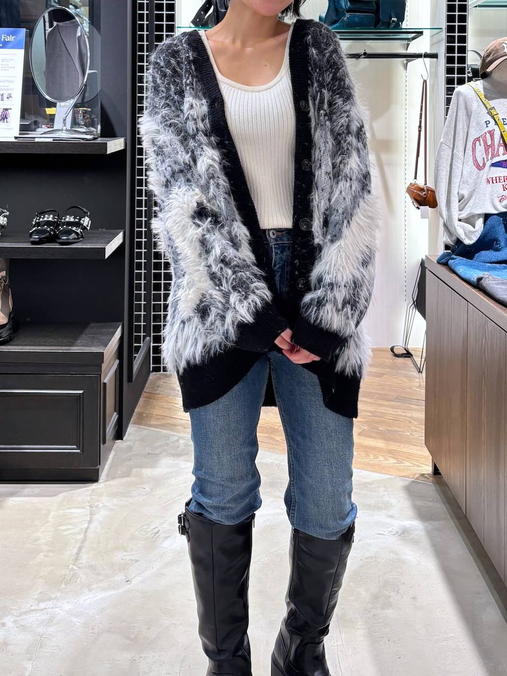 ホワイト系のタンクトップ、ブラック系のカーディガン/ボレロ、ブラック系のブーツを着用したレディースの秋コーディネートの2枚目の写真