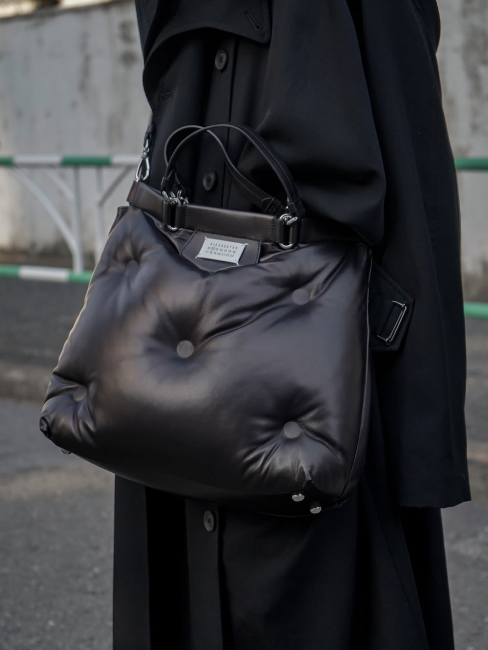 ブラック系のショルダーバッグ、ブラック系のトレンチコート、ブラック系のスラックスを着用したメンズの春コーディネートの3枚目の写真