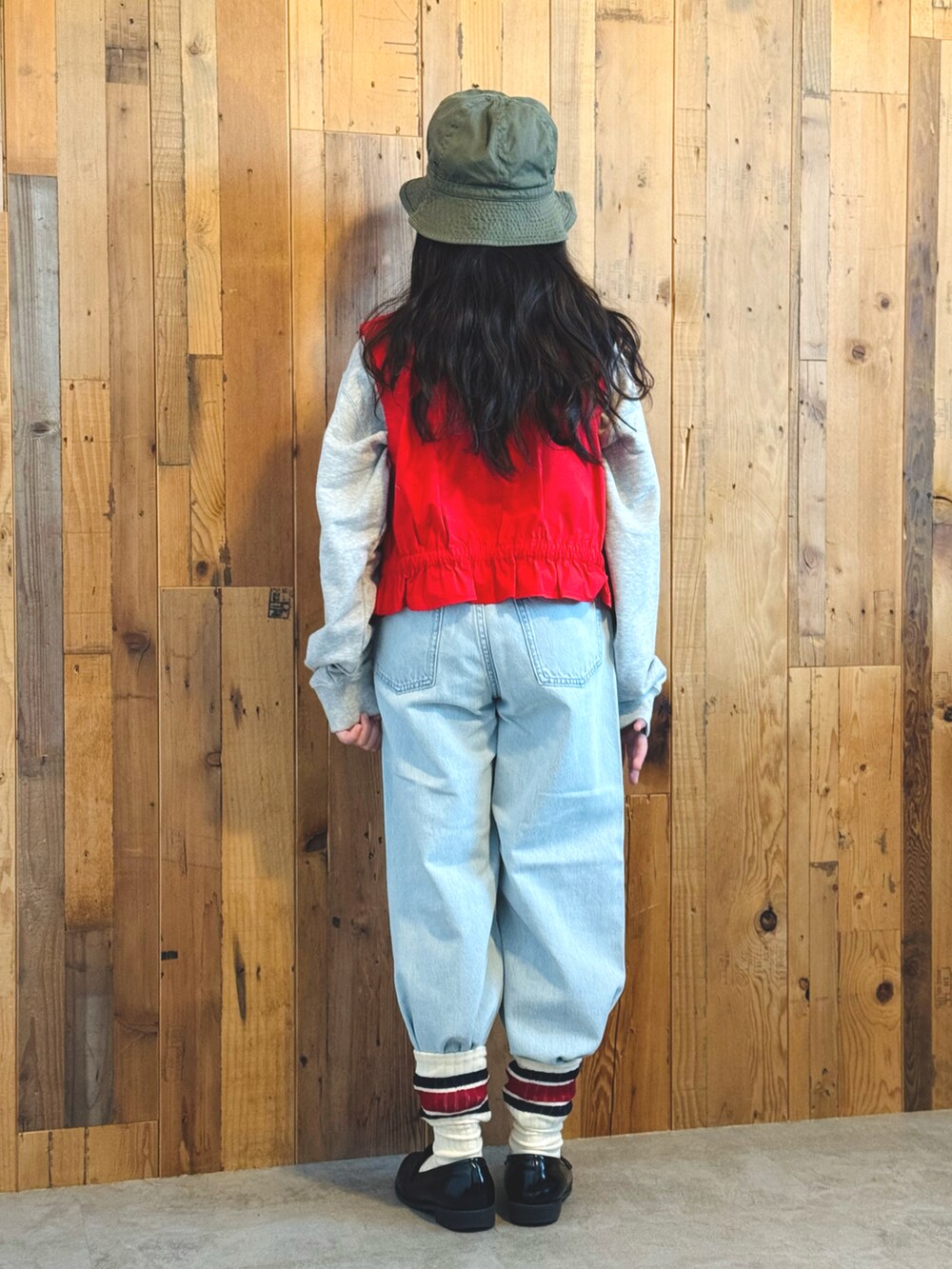 レッド系のベスト、グレー系のスウェット、ブルー系のデニムパンツを着用したキッズの冬コーディネートの3枚目の写真