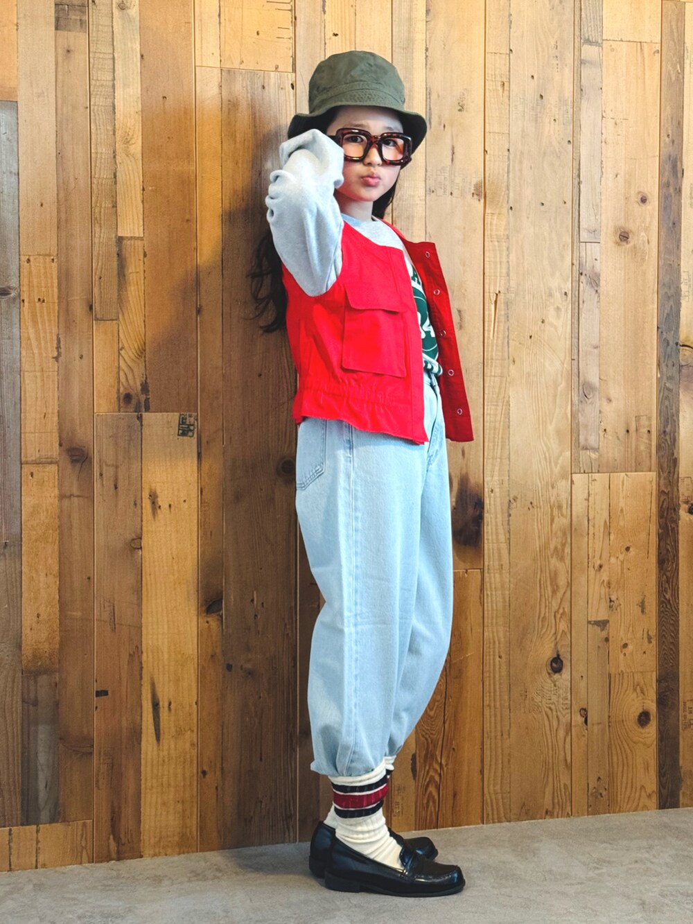 レッド系のベスト、グレー系のスウェット、ブルー系のデニムパンツを着用したキッズの冬コーディネートの4枚目の写真