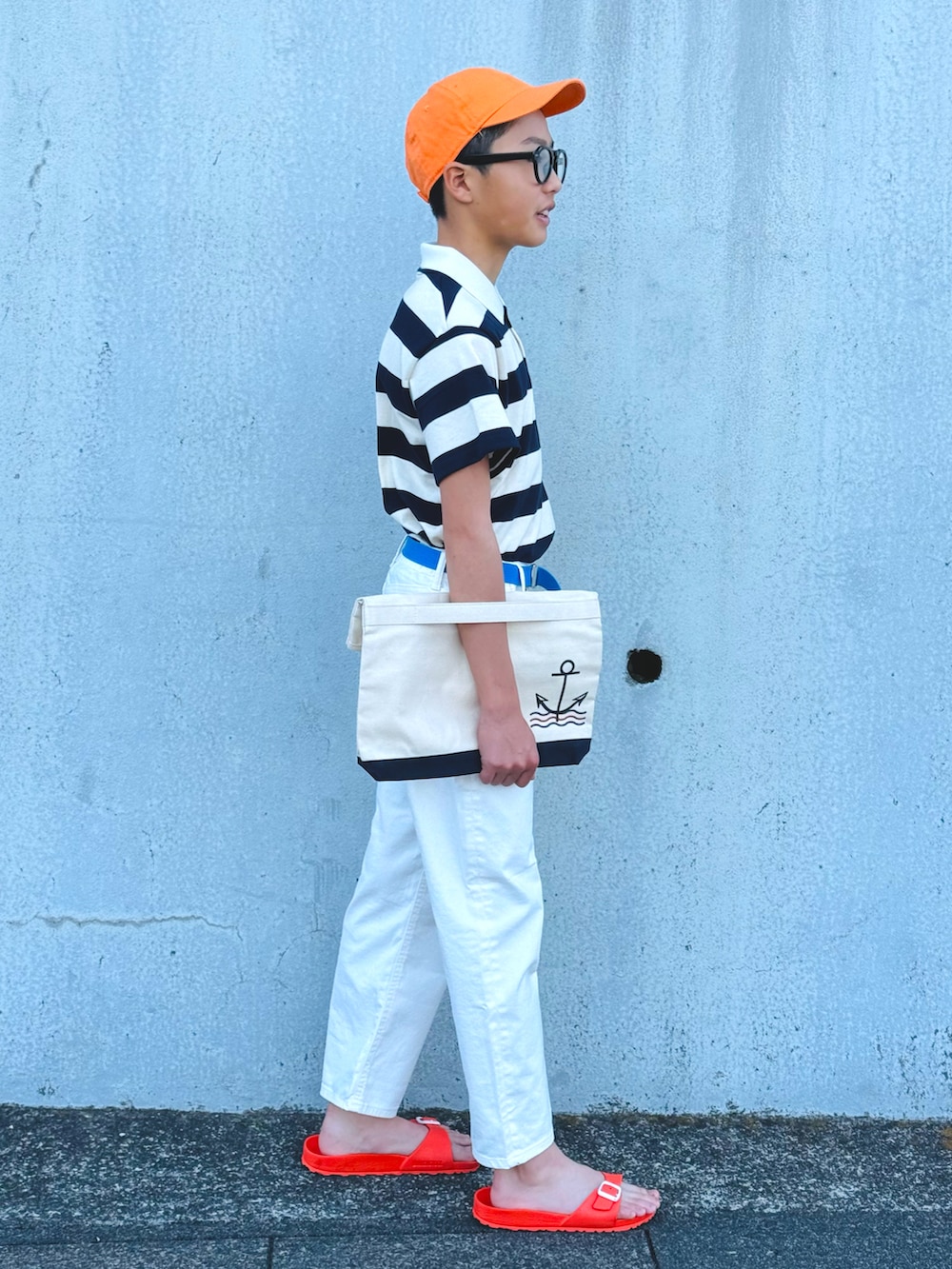 ホワイト系のポロシャツ、ホワイト系のデニムパンツ、オレンジ系のサンダルを着用したキッズの春コーディネートの2枚目の写真