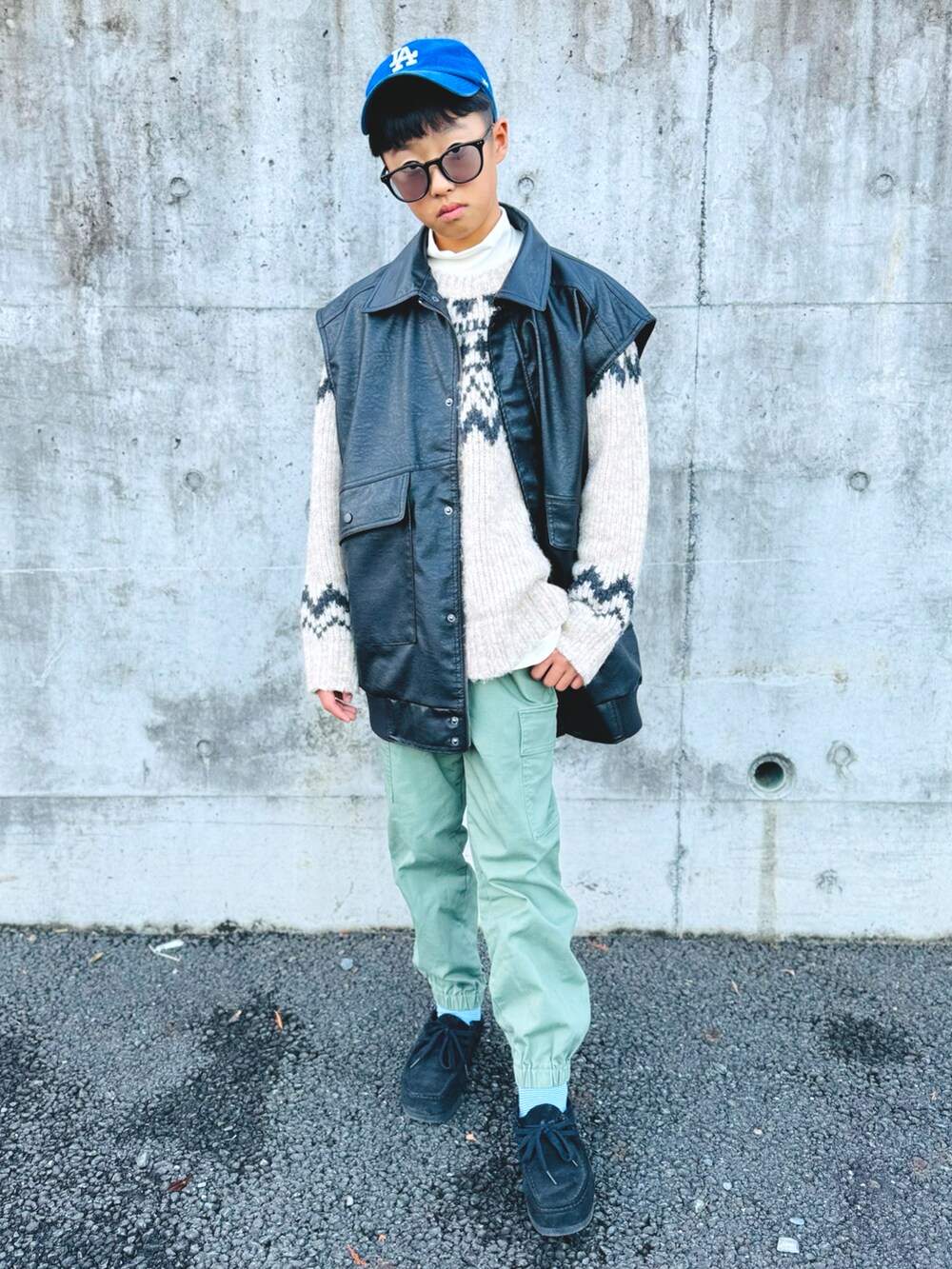 ブラック系のベスト、グリーン系のカーゴパンツ、ブラック系のモカシン/デッキシューズを着用したキッズの冬コーディネートの2枚目の写真