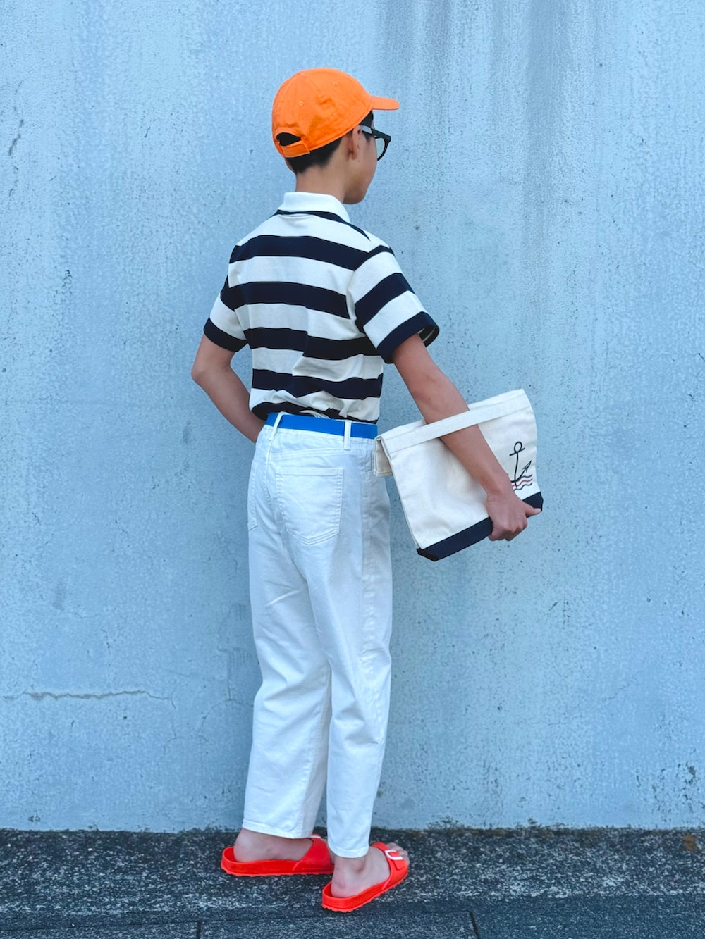 ホワイト系のポロシャツ、ホワイト系のデニムパンツ、オレンジ系のサンダルを着用したキッズの春コーディネートの3枚目の写真