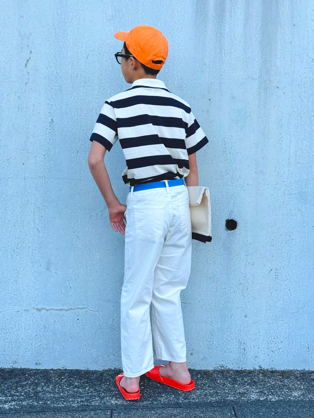 ホワイト系のポロシャツ、ホワイト系のデニムパンツ、オレンジ系のサンダルを着用したキッズの春コーディネートの5枚目の写真