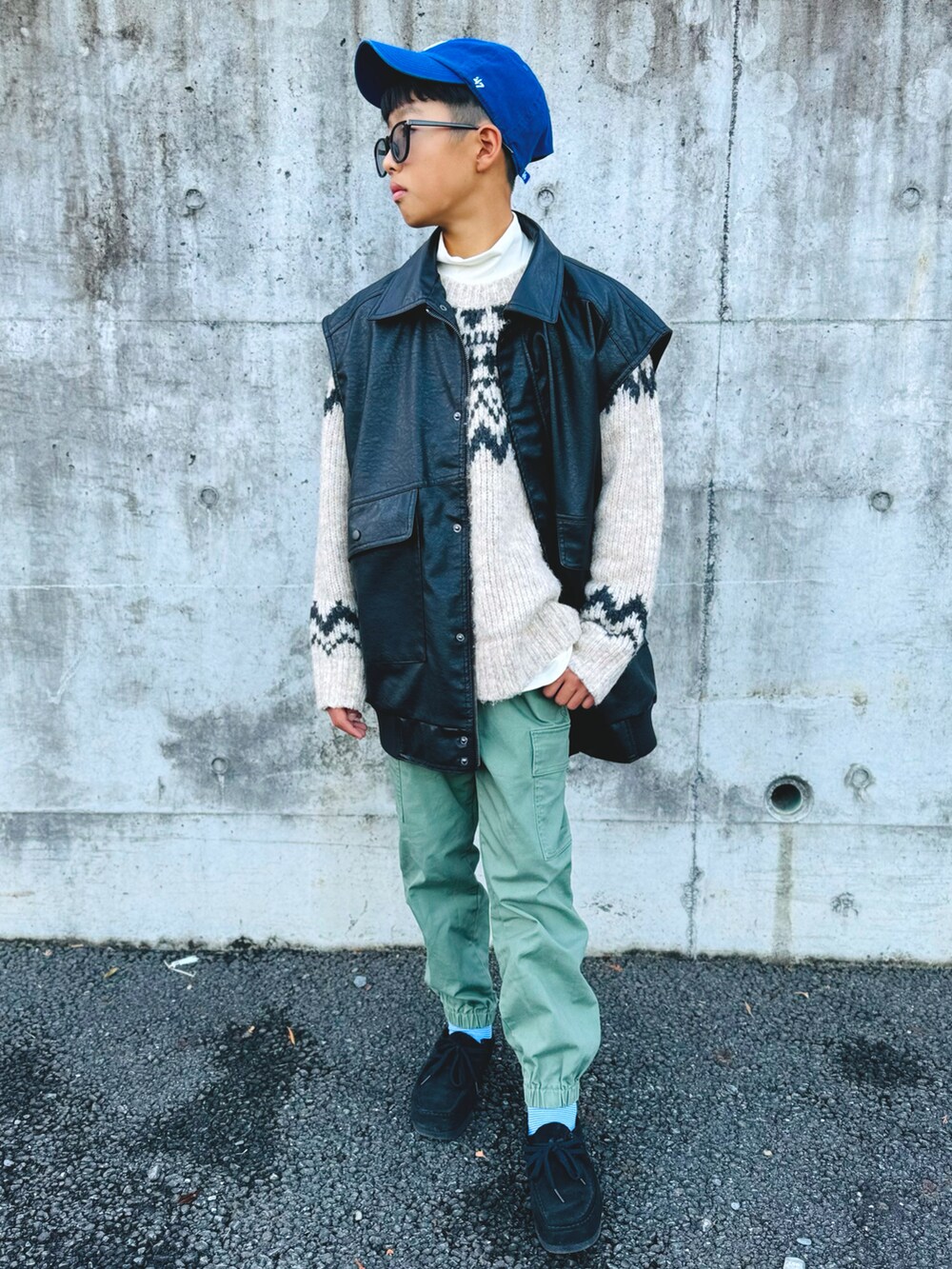 ブラック系のベスト、グリーン系のカーゴパンツ、ブラック系のモカシン/デッキシューズを着用したキッズの冬コーディネートの3枚目の写真