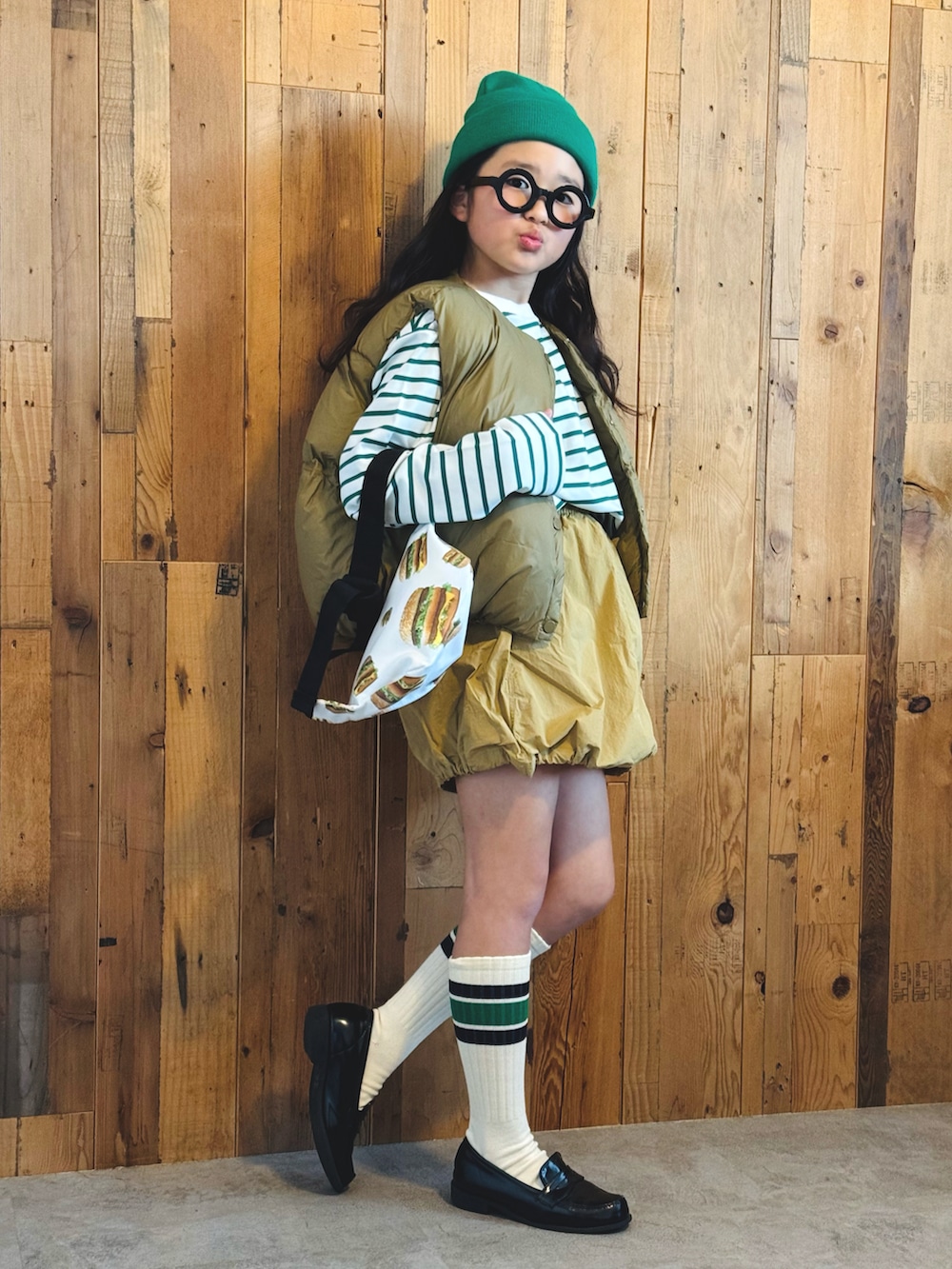 グリーン系のTシャツ/カットソー、ベージュ系のベスト、ベージュ系のスカートを着用したキッズの冬コーディネートの3枚目の写真