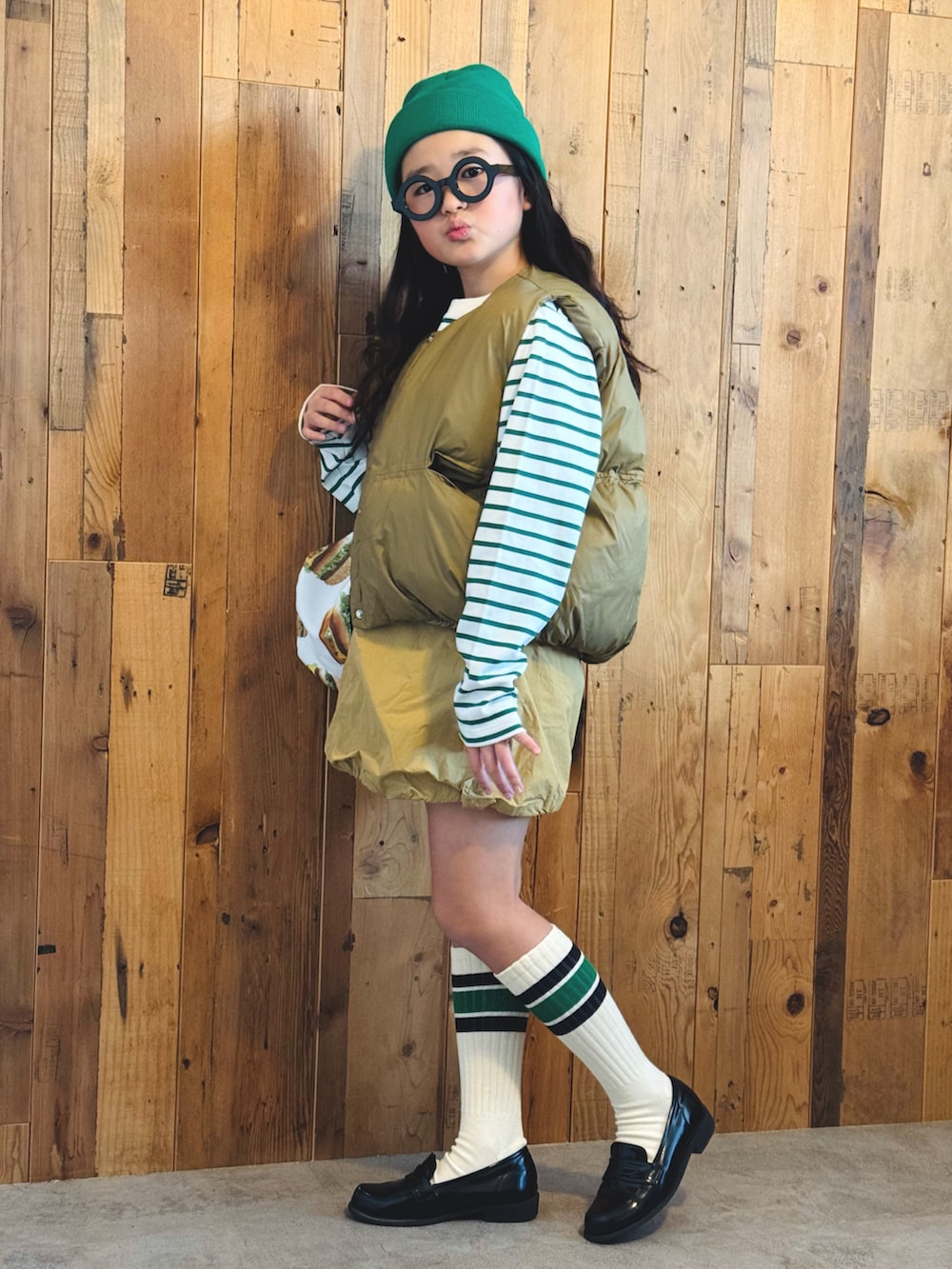 グリーン系のTシャツ/カットソー、ベージュ系のベスト、ベージュ系のスカートを着用したキッズの冬コーディネートの2枚目の写真