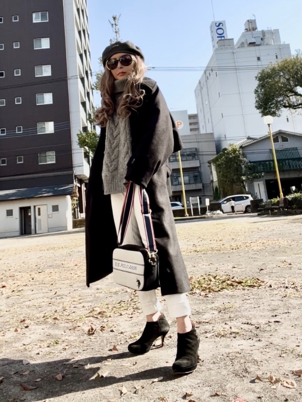 ブラック系のステンカラーコート、ホワイト系のデニムパンツ、ホワイト系のショルダーバッグを着用したレディースの秋コーディネートの2枚目の写真