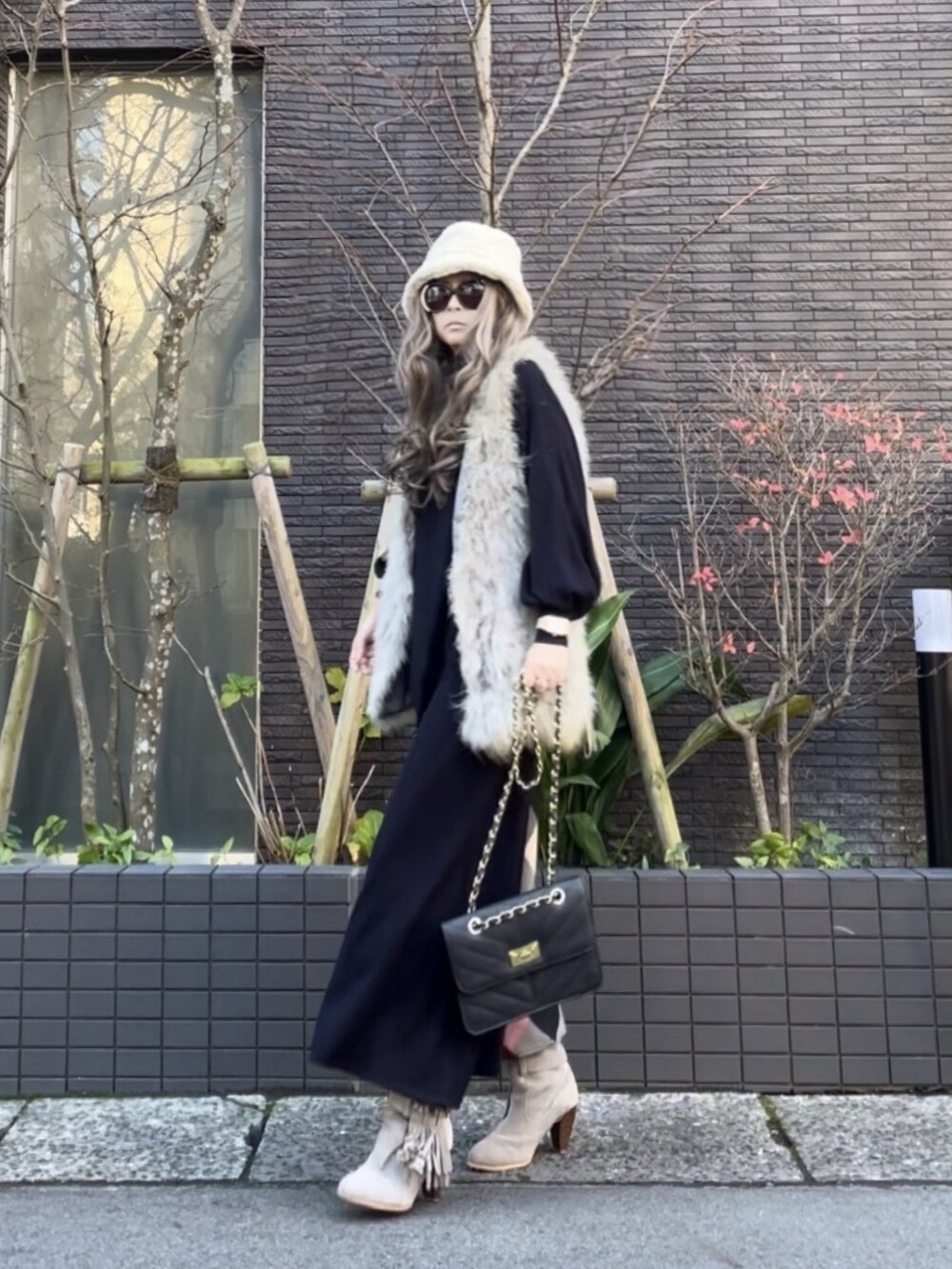 グレー系のベスト、ブルー系のワンピース、グレー系のブーツを着用したレディースの冬コーディネートの4枚目の写真