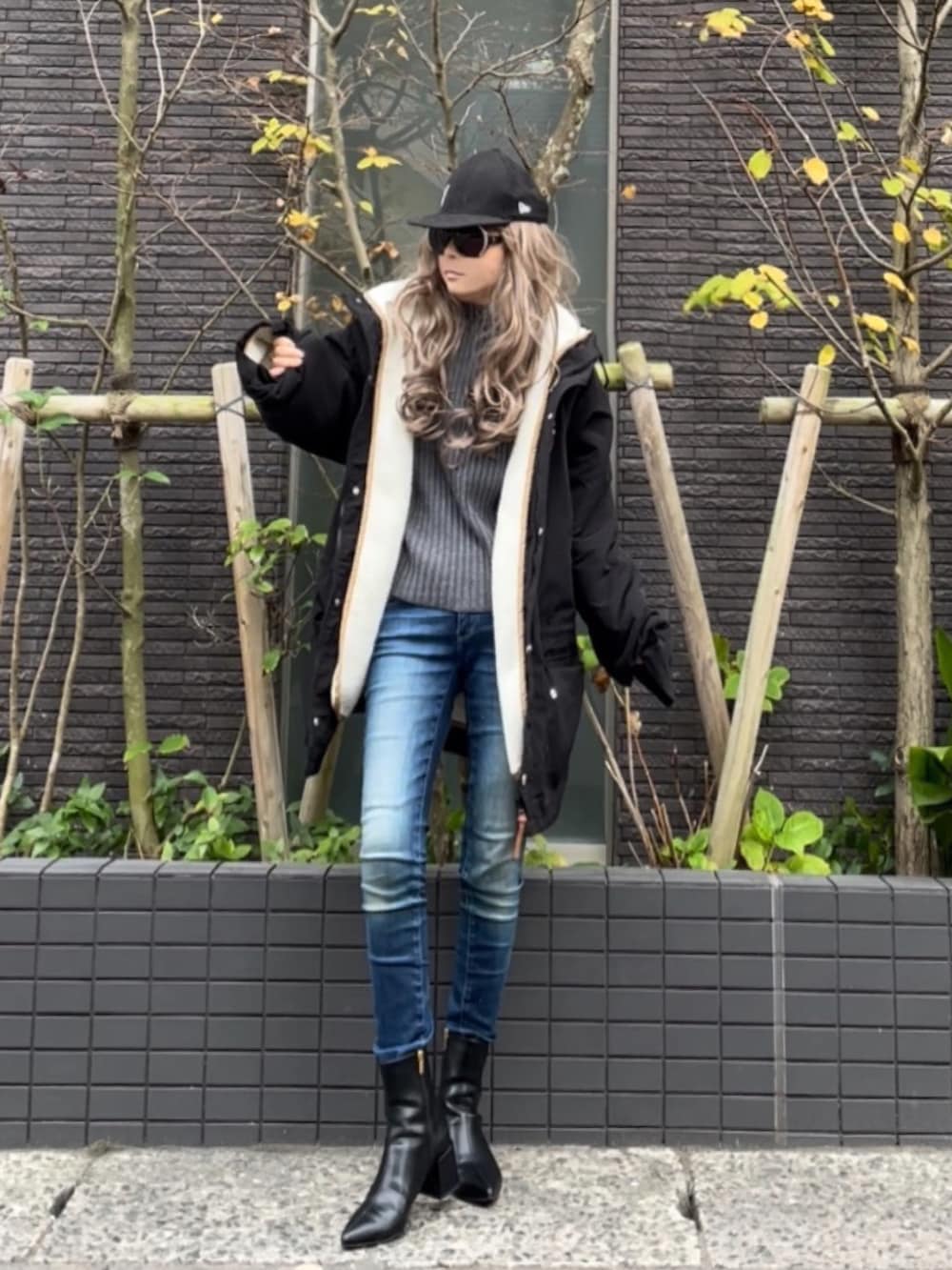 ブラック系のマウンテンパーカー、グレー系のニット/セーター、ブルー系のデニムパンツを着用したレディースの秋コーディネートの4枚目の写真