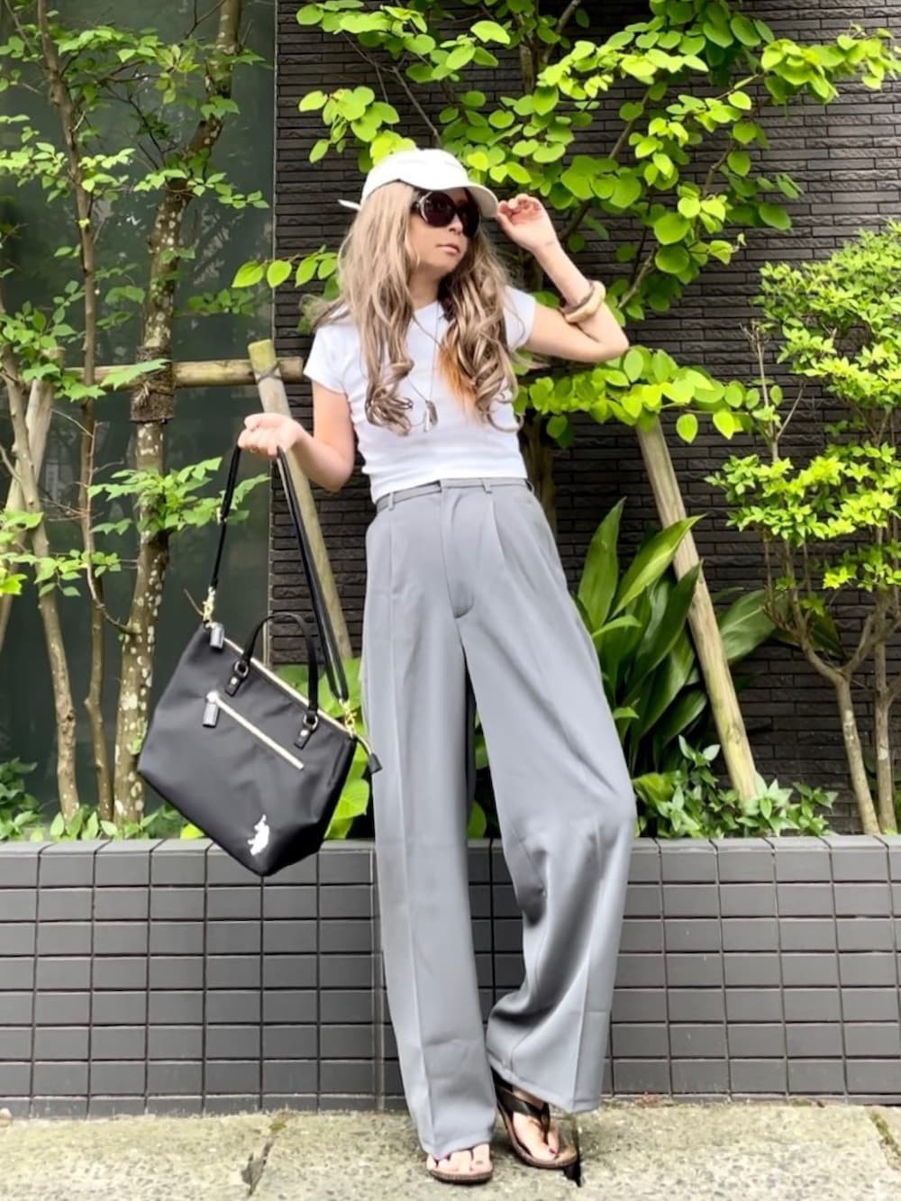 ホワイト系のTシャツ/カットソー、ブラック系のトートバッグ、グレー系のスラックスを着用したレディースの夏コーディネートの3枚目の写真