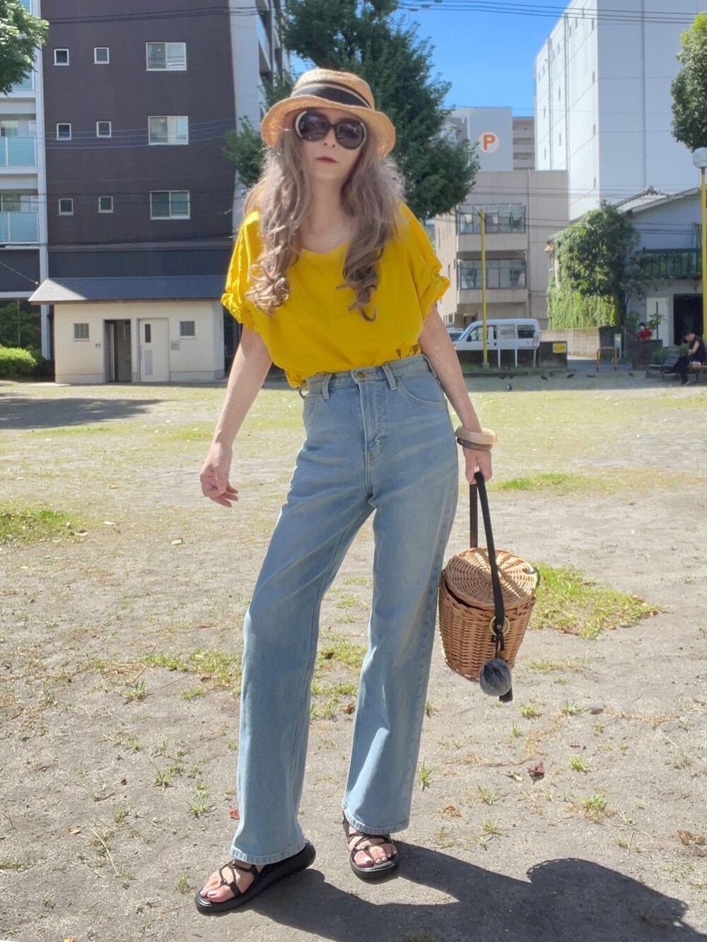 イエロー系のTシャツ/カットソー、ブルー系のデニムパンツ、ブラック系のかごバッグを着用したレディースの夏コーディネートの3枚目の写真