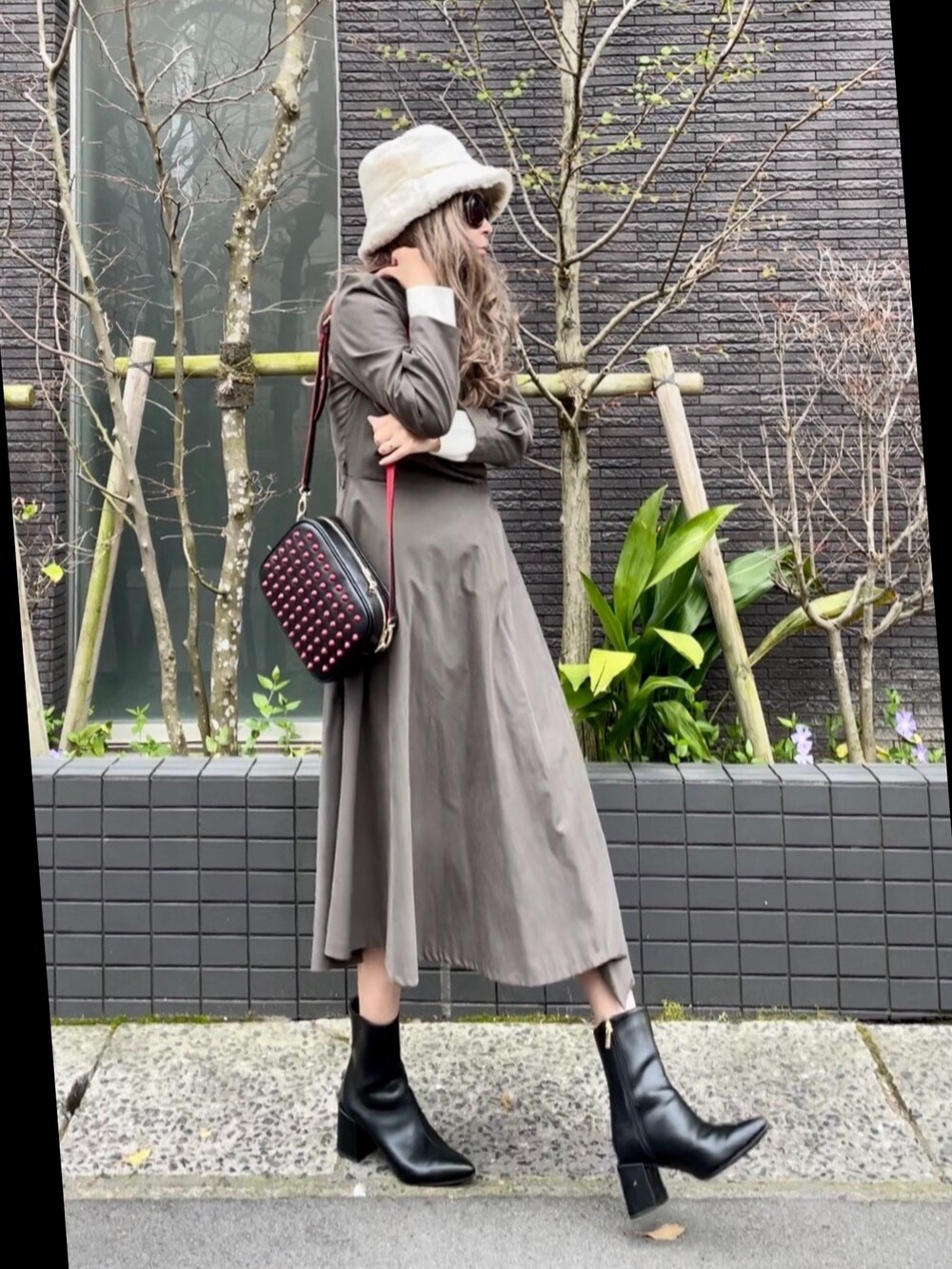 グレー系のワンピース、ブラック系のショルダーバッグ、ブラック系のブーツを着用したレディースの春コーディネートの2枚目の写真