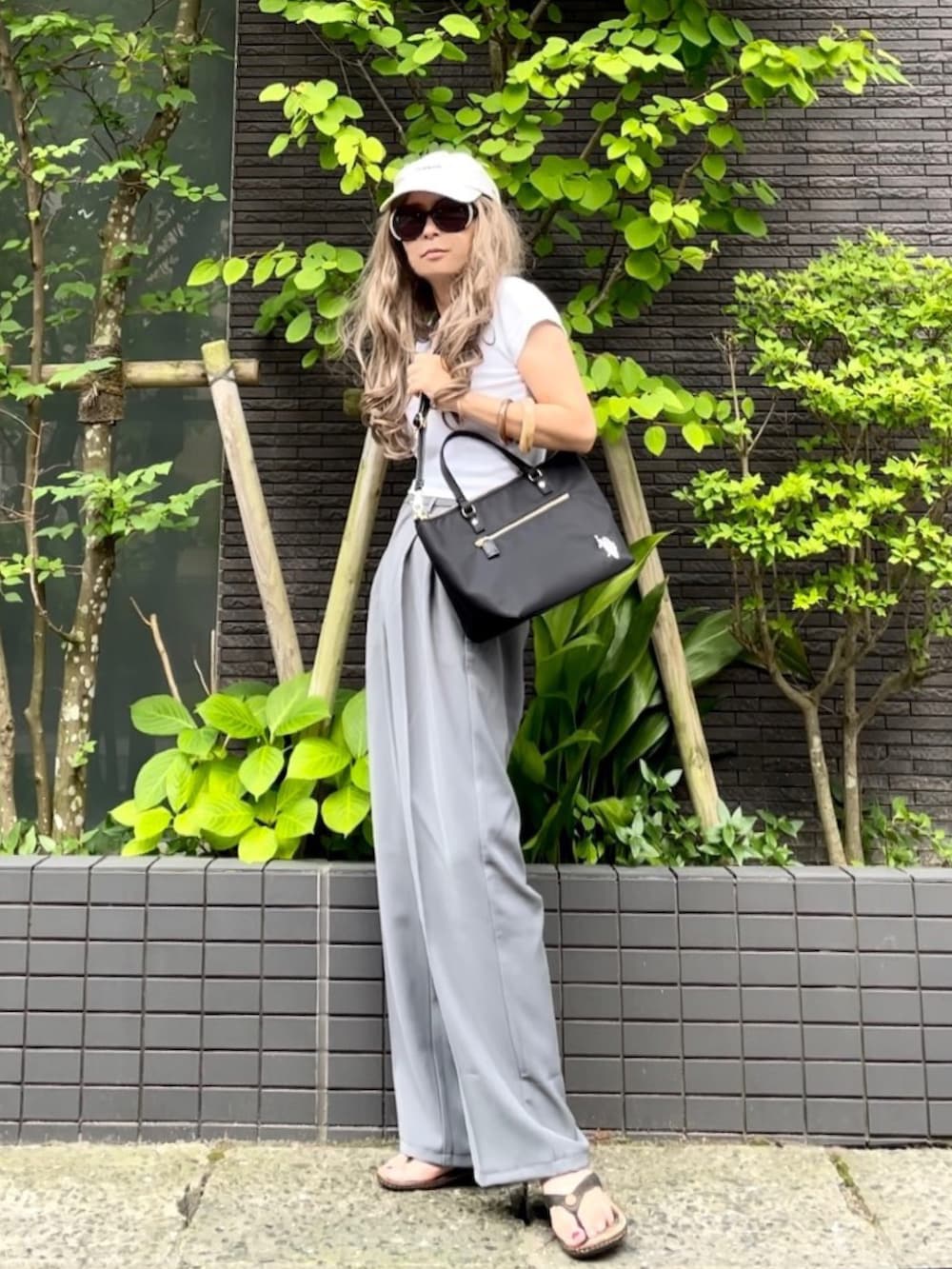 ホワイト系のTシャツ/カットソー、ブラック系のトートバッグ、グレー系のスラックスを着用したレディースの夏コーディネートの2枚目の写真