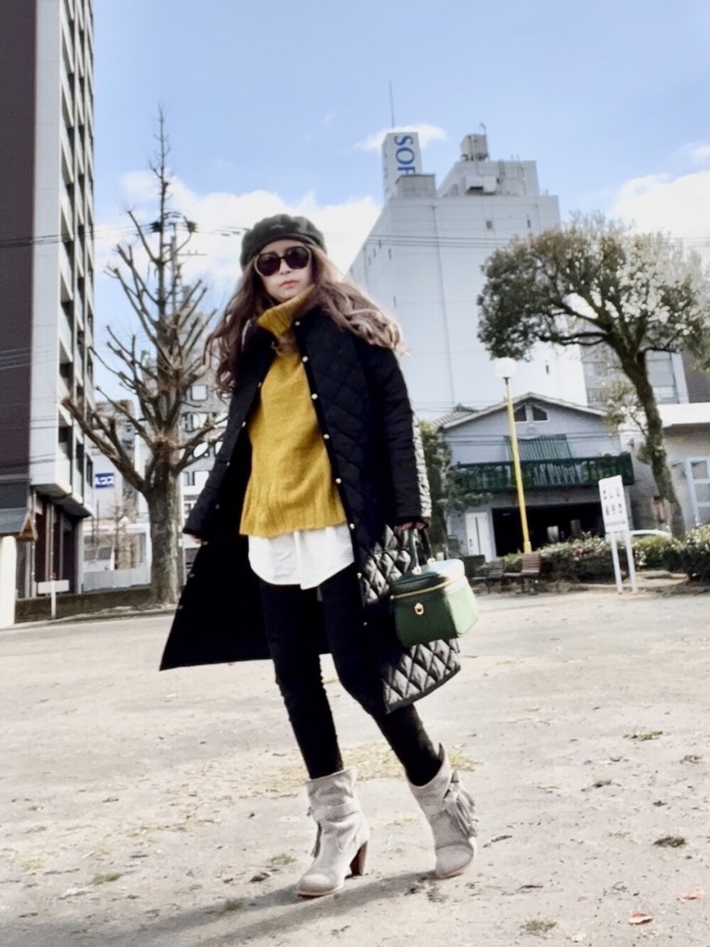 ブラック系のノーカラーコート、イエロー系のニット/セーター、ブラック系のデニムパンツを着用したレディースの冬コーディネートの2枚目の写真