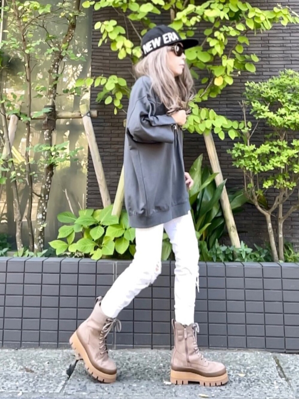 グレー系のスウェット、ホワイト系のバッグ、ホワイト系のデニムパンツを着用したレディースの夏コーディネートの2枚目の写真