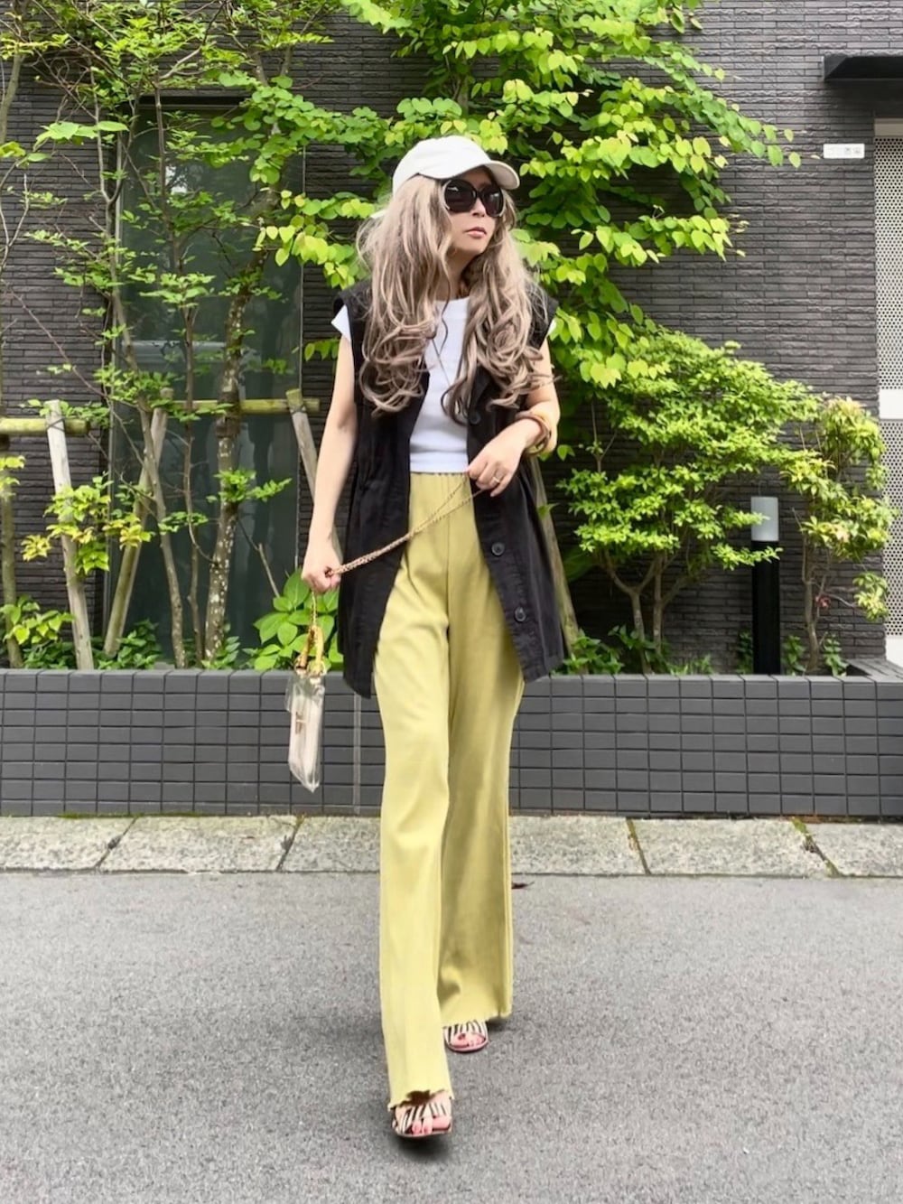 ホワイト系のTシャツ/カットソー、ブラック系のベスト、イエロー系のパンツを着用したレディースの春コーディネートの2枚目の写真