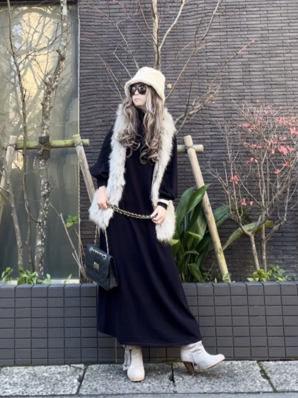 グレー系のベスト、ブルー系のワンピース、グレー系のブーツを着用したレディースの冬コーディネートの5枚目の写真