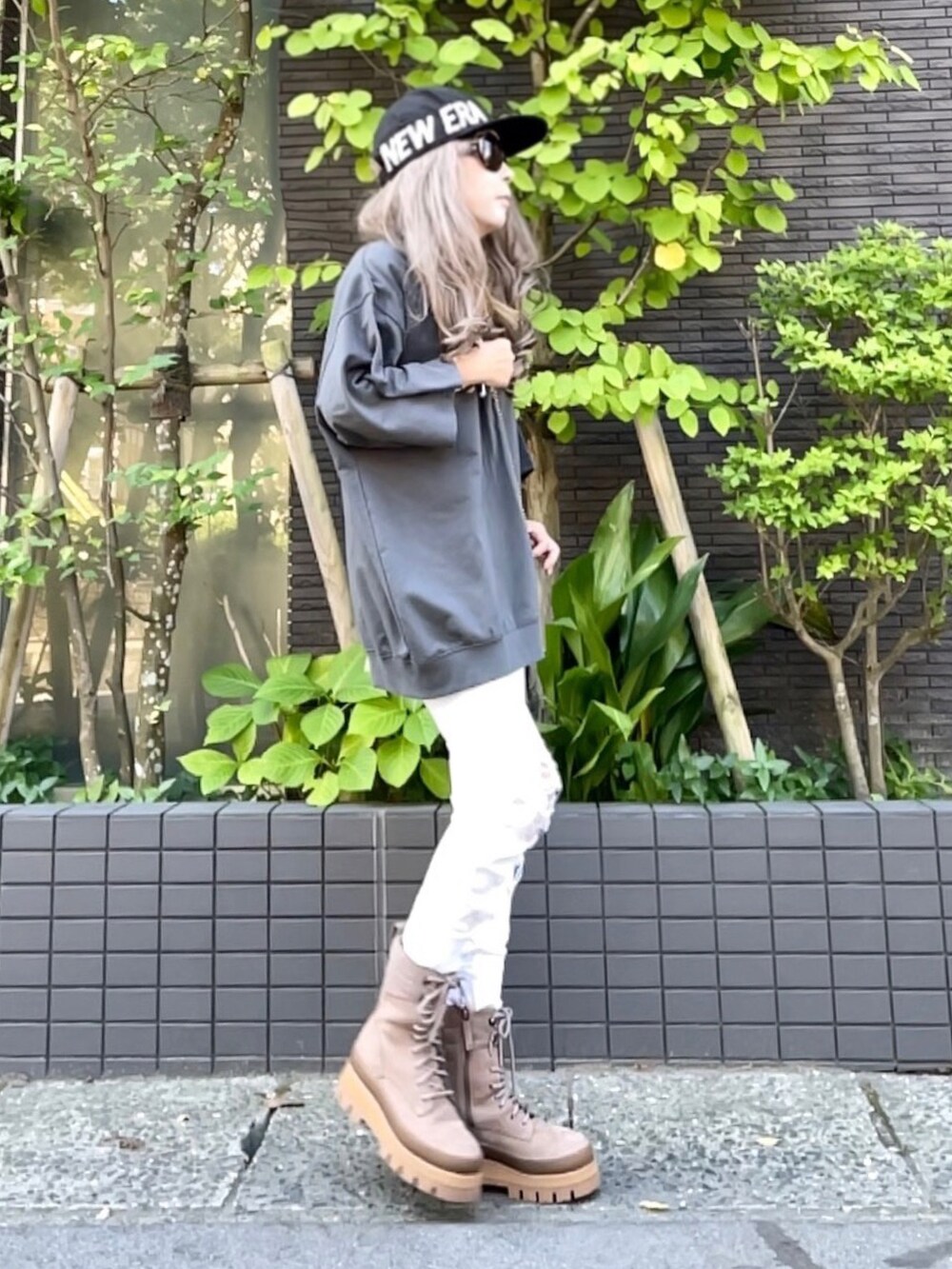 グレー系のスウェット、ホワイト系のバッグ、ホワイト系のデニムパンツを着用したレディースの夏コーディネートの4枚目の写真