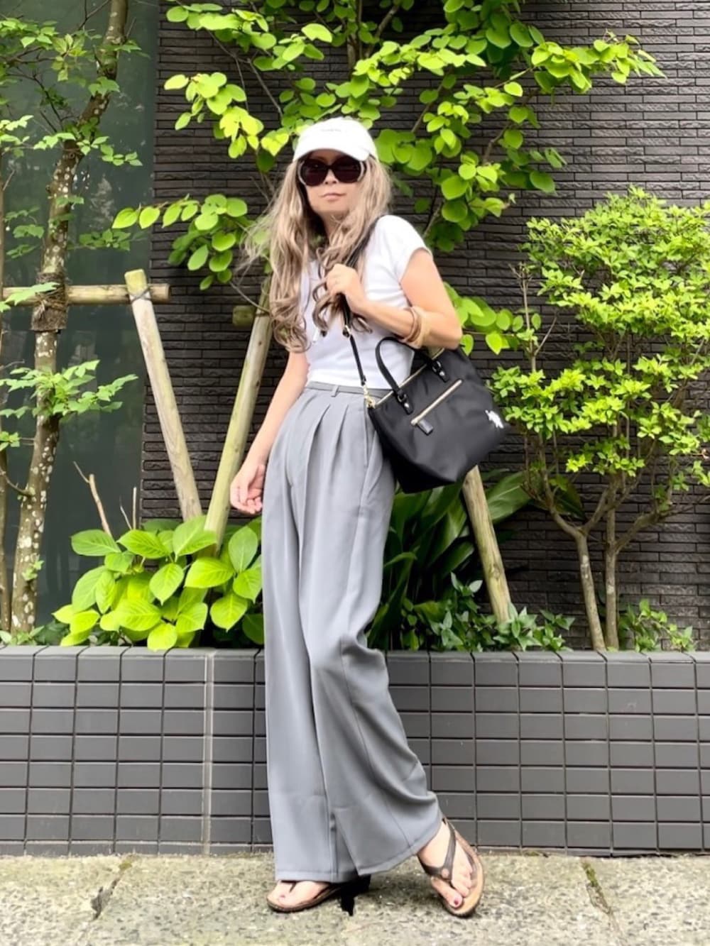 ホワイト系のTシャツ/カットソー、ブラック系のトートバッグ、グレー系のスラックスを着用したレディースの夏コーディネートの4枚目の写真