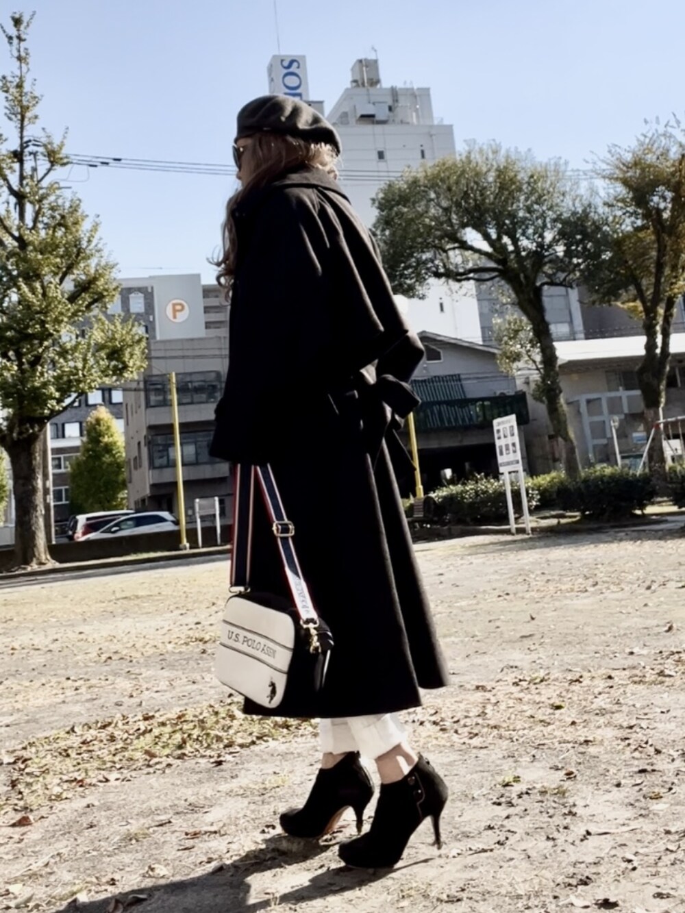 ブラック系のステンカラーコート、ホワイト系のデニムパンツ、ホワイト系のショルダーバッグを着用したレディースの秋コーディネートの3枚目の写真