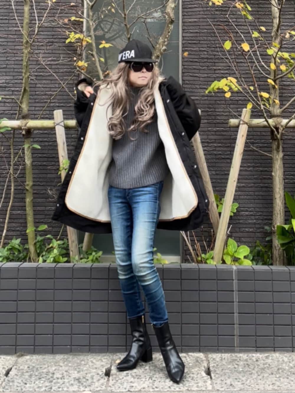 ブラック系のマウンテンパーカー、グレー系のニット/セーター、ブルー系のデニムパンツを着用したレディースの秋コーディネートの2枚目の写真