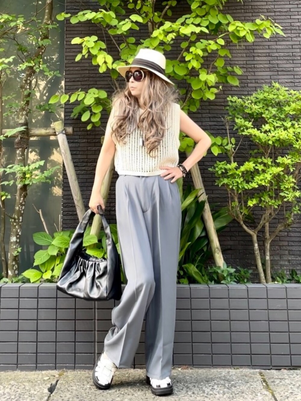 ブラック系のタンクトップ、ホワイト系のベスト、グレー系のスラックスを着用したレディースの夏コーディネートの3枚目の写真