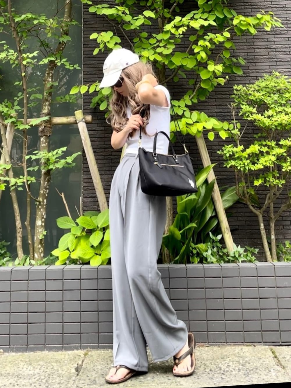 ホワイト系のTシャツ/カットソー、ブラック系のトートバッグ、グレー系のスラックスを着用したレディースの夏コーディネートの5枚目の写真