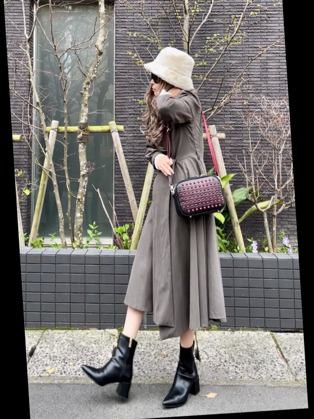 グレー系のワンピース、ブラック系のショルダーバッグ、ブラック系のブーツを着用したレディースの春コーディネートの3枚目の写真