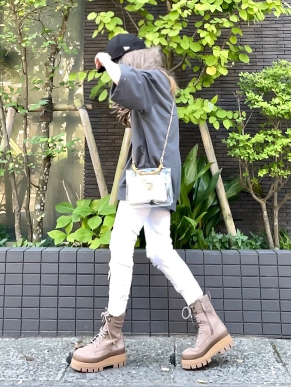 グレー系のスウェット、ホワイト系のバッグ、ホワイト系のデニムパンツを着用したレディースの夏コーディネートの3枚目の写真