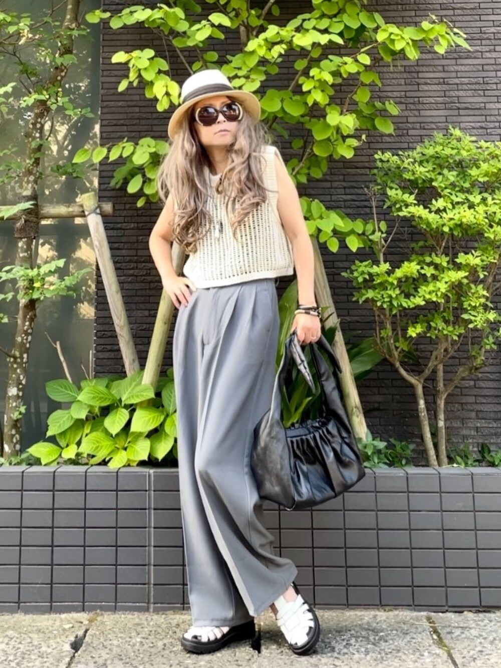 ブラック系のタンクトップ、ホワイト系のベスト、グレー系のスラックスを着用したレディースの夏コーディネートの2枚目の写真