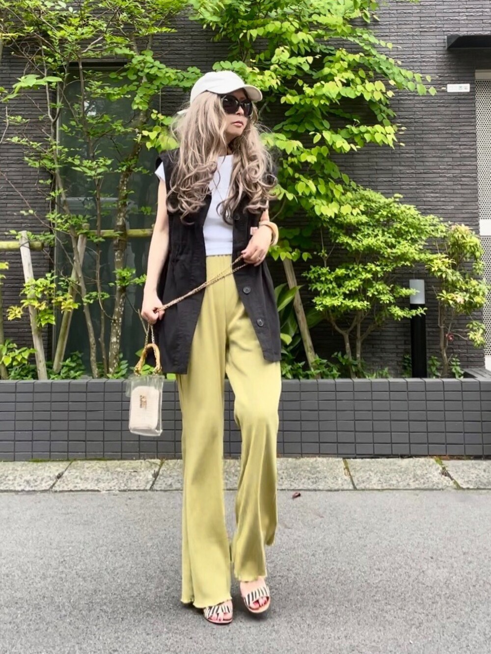 ホワイト系のTシャツ/カットソー、ブラック系のベスト、イエロー系のパンツを着用したレディースの春コーディネートの3枚目の写真