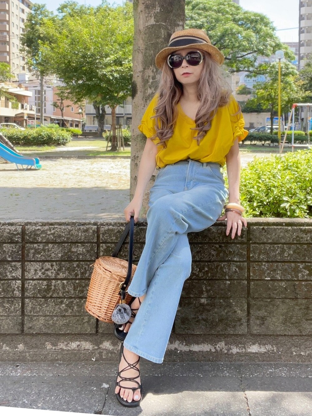 イエロー系のTシャツ/カットソー、ブルー系のデニムパンツ、ブラック系のかごバッグを着用したレディースの夏コーディネートの2枚目の写真