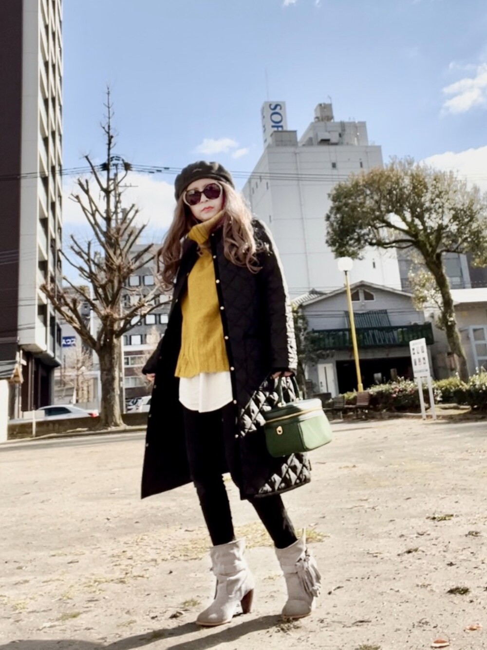 ブラック系のノーカラーコート、イエロー系のニット/セーター、ブラック系のデニムパンツを着用したレディースの冬コーディネートの3枚目の写真