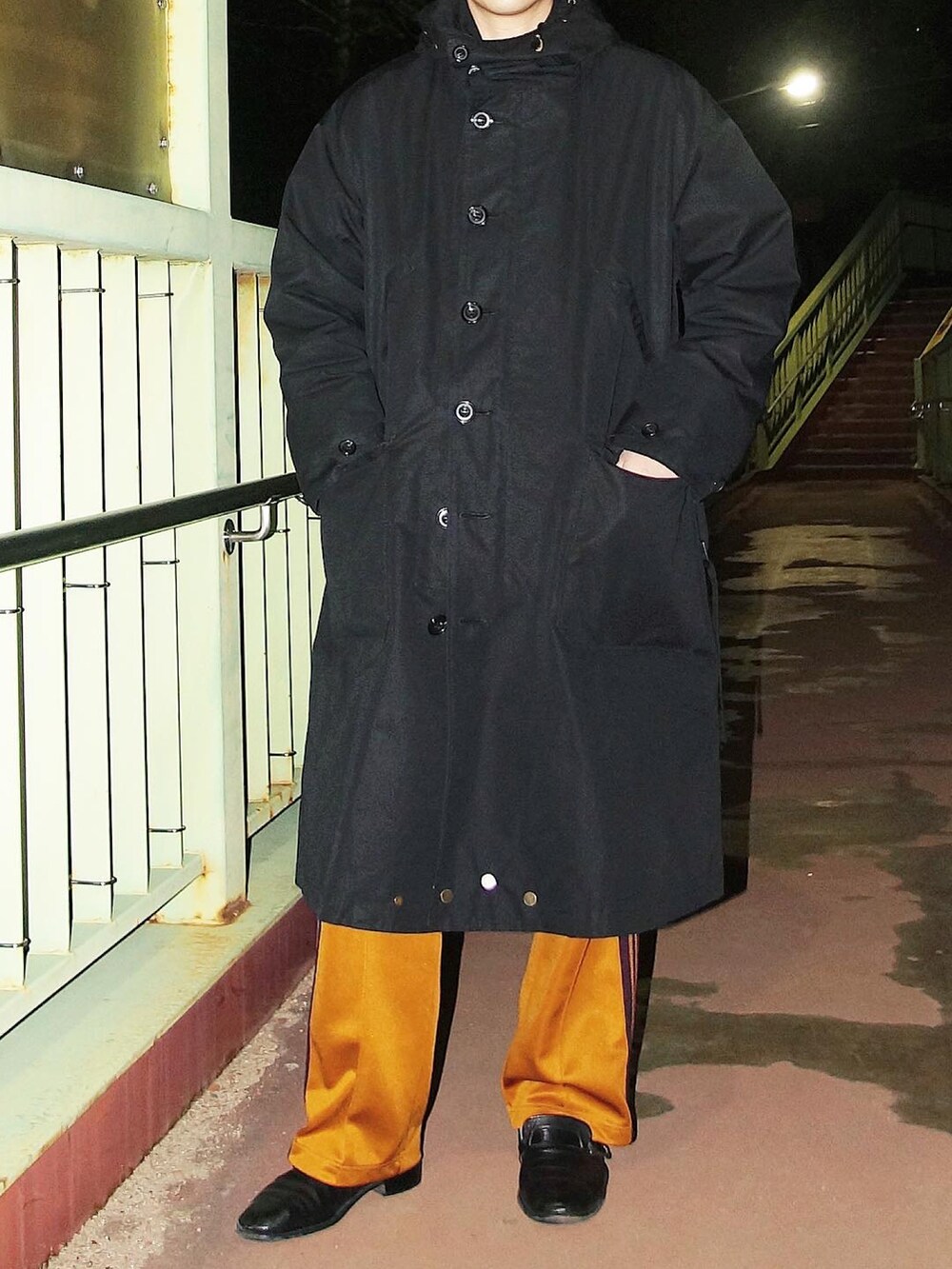 ブラック系のモッズコート、イエロー系のスウェットパンツ、ブラック系のローファーを着用したメンズの春コーディネートの2枚目の写真