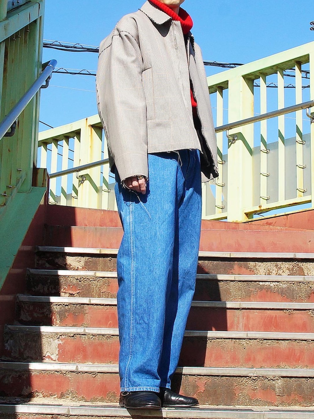 レッド系のニット/セーター、グレー系のブルゾン、ブルー系のデニムパンツを着用したメンズの冬コーディネートの2枚目の写真