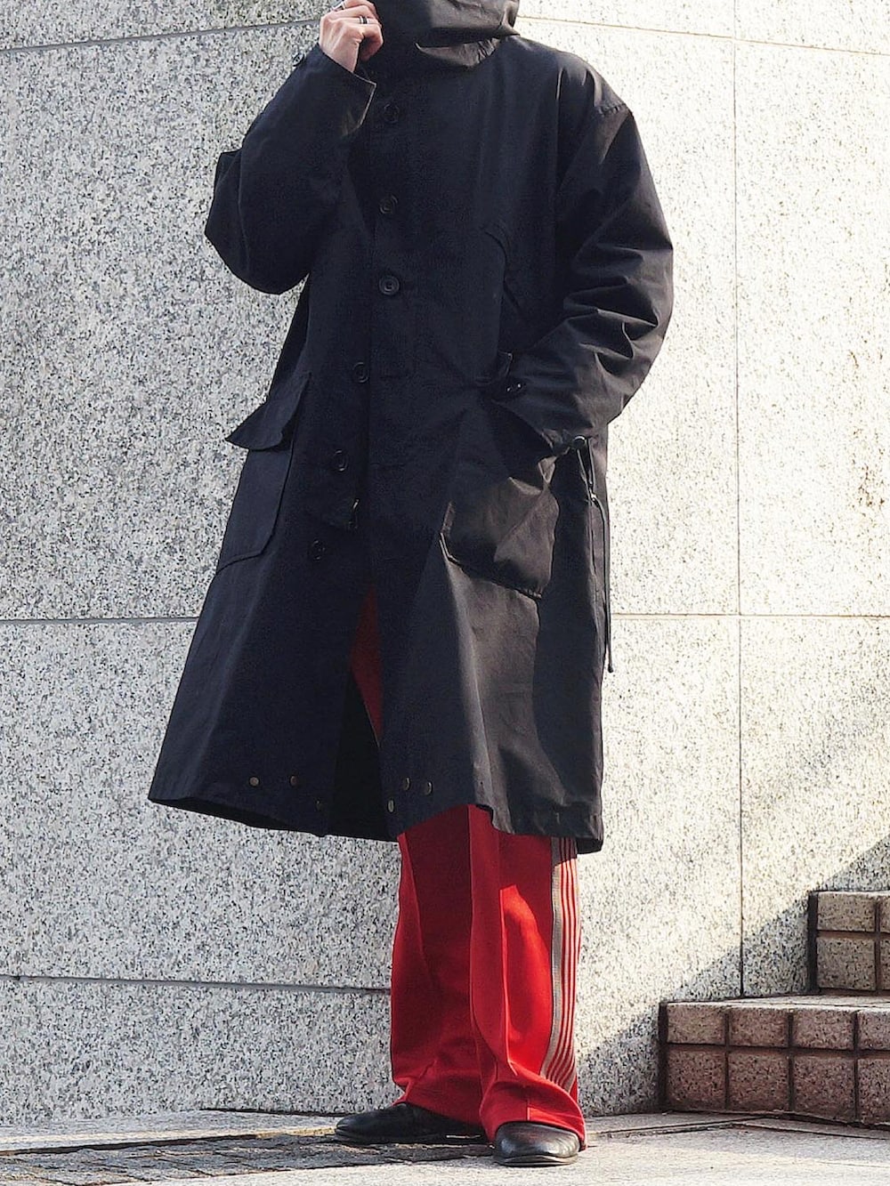 ブラック系のモッズコート、レッド系のその他パンツ、ブラック系のローファーを着用したメンズの冬コーディネートの3枚目の写真