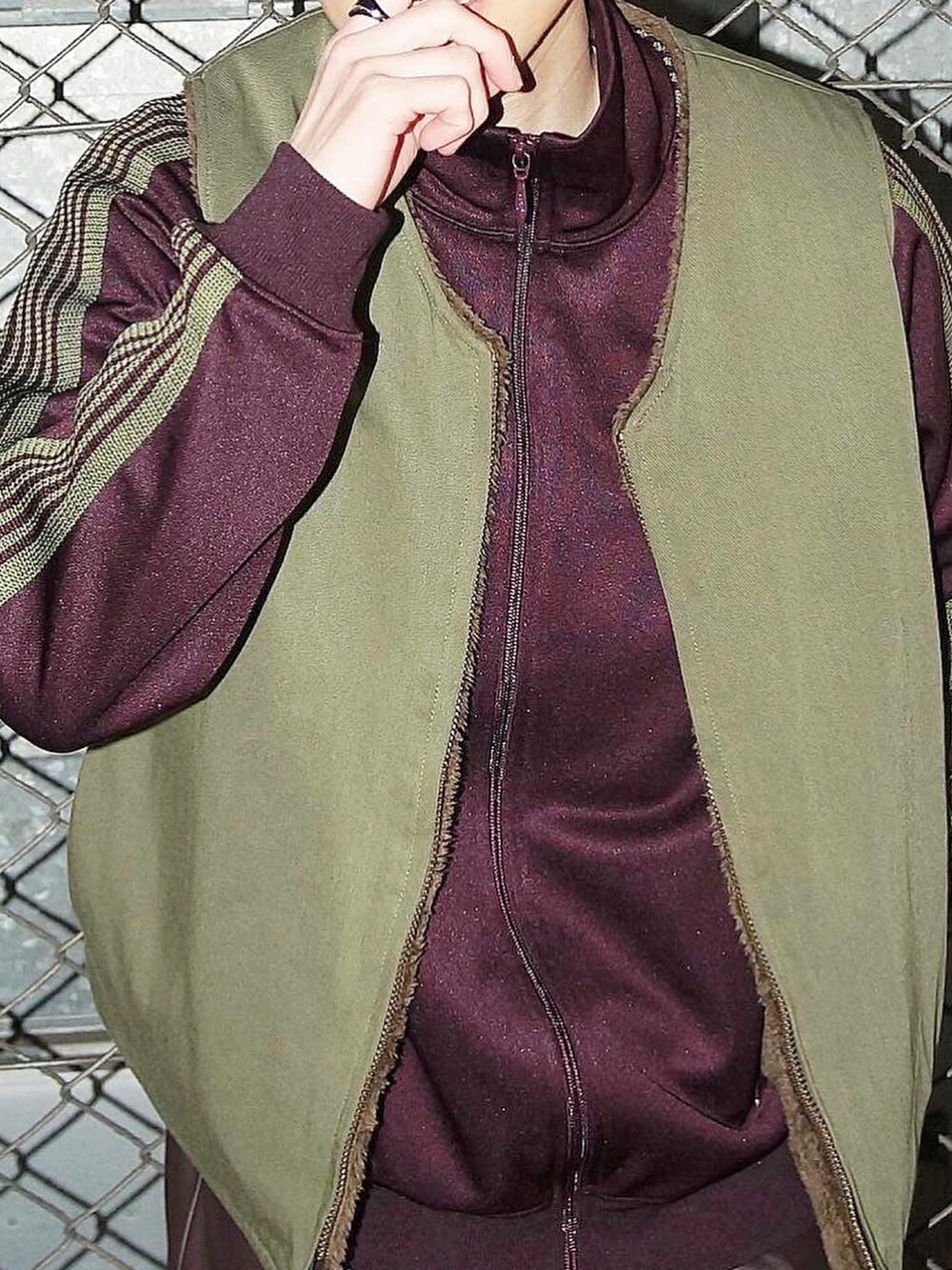 ブラウン系のパンツ、パープル系のジャージ、グリーン系のベストを着用したメンズの冬コーディネートの3枚目の写真