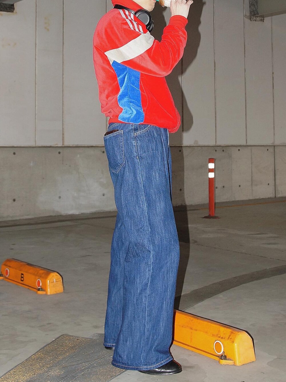 レッド系のジャージ、ブルー系のデニムパンツを着用したメンズの冬コーディネートの2枚目の写真